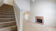 Located at 9818 E 19th St N in Wichita, Kansas, this two-story home offers 2 bedrooms and 3 bathrooms across two well-proportioned floors. The main level is anchored by a striking living room with soaring vaulted ceilings, a ceiling fan, soft carpet flooring, and a classic brick wood-burning fireplace with a white-painted mantel. French doors allow natural light to fill the space, enhancing its open and airy feel. Built-in shelving adds a functional architectural touch near the staircase. The kitchen features white cabinetry, tile flooring, laminate countertops, and a full suite of appliances including a refrigerator, range, and microwave. A dedicated laundry area on the main level houses a full-size washer and dryer with overhead cabinetry for added storage. Upstairs, the primary bedroom is generously sized and accompanied by an en-suite bathroom featuring a dual-sink vanity with white cabinetry, wall-mounted lighting, a large mirror, and a separate water closet with tile flooring. A walk-in closet adds practical convenience. The second bedroom is carpeted and well-proportioned with neutral tones throughout. Three bathrooms in total serve the home's two floors comfortably. The overall palette of warm neutrals and clean finishes creates a cohesive, move-in-ready atmosphere throughout.