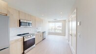 Located along North Broad Street in Philadelphia's vibrant Northern Liberties neighborhood, this thoughtfully designed one-bedroom, one-bathroom unit offers a clean, contemporary aesthetic throughout. Light-toned hardwood flooring flows seamlessly across the entire space, enhancing the bright, airy atmosphere created by recessed lighting and generous natural light.

The open-plan kitchen and living area serves as the heart of the unit. The kitchen is outfitted with light birch wood cabinetry, stainless steel appliances including a range, microwave, dishwasher, and refrigerator, and a white subway tile backsplash that adds texture without sacrificing simplicity. A large picture window in the living area frames sweeping views of the Philadelphia skyline and surrounding rooftops, filling the space with abundant natural light.

The bedroom is a calm, well-proportioned retreat featuring its own oversized window with the same striking city views, light wood flooring, and a closet for convenient storage. A second closet and in-unit laundry further enhance everyday functionality.

The bathroom is finished in crisp white tile with a walk-in glass-enclosed shower, modern chrome fixtures, and clean, minimalist detailing. The overall design palette — whites, naturals, and soft woods — gives the entire unit a fresh, modern character well-suited to urban living.