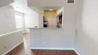This two-story residence offers a thoughtfully designed layout with distinct living areas spread across both levels, connected by a staircase visible in the floorplan. The main living area flows openly into the kitchen, which is separated by a half-wall peninsula topped with granite countertops. The kitchen is well-equipped with rich, dark cabinetry, stainless steel appliances including a range and over-the-range microwave, a double basin sink, and a classic white tile backsplash. Wood-style flooring runs throughout the main living areas, adding warmth and cohesion to the space.

The bedrooms are carpeted and finished in neutral tones, each featuring six-panel doors and ceiling vents. One bedroom includes a ceiling fan with a light fixture and a window that brings in natural light. The bathroom is outfitted with matching dark cabinetry, granite countertops, a framed mirror, gold-toned fixtures, and a full tub-shower combination. Throughout the home, a consistent neutral color palette of warm beiges and soft grays creates a clean, cohesive aesthetic, while white trim and millwork provide crisp contrast against the walls.