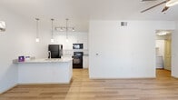 Located at 7300 N Silverbell Rd in Marana, AZ, this single-story, one-bedroom, one-bathroom unit offers a well-designed layout that maximizes every square foot. The open-concept living and dining area is anchored by light wood-style flooring, crisp white walls, and a ceiling fan, creating a bright and airy atmosphere. A sliding glass door leads to an outdoor balcony, filling the space with natural light. The dining area features a stylish pendant chandelier and a window with outdoor views. The kitchen is equipped with granite-style countertops, white shaker cabinetry extending to the ceiling, black appliances including a refrigerator, electric range, and built-in microwave, plus a peninsula with a sink that serves as a functional divide between the kitchen and dining space. The bedroom is carpeted, includes a ceiling fan, and receives natural light through a large window. A spacious walk-in closet with wrap-around shelving and hanging rods provides generous storage. The bathroom offers a full tub and shower combination with white tile surround, wood-style flooring, and brushed nickel fixtures. A dedicated in-unit laundry area accommodates a full-size washer and dryer side by side, adding everyday convenience to this thoughtfully appointed home.
