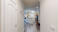 Located at 59 Summerlake Cir in Ridgeland, SC, this well-appointed single-story home offers two bedrooms, two bathrooms, and a thoughtfully designed layout. The living room makes a strong first impression with its tray ceiling, crown molding, and wood-look flooring that extends throughout the main living areas, creating a warm and cohesive aesthetic. The kitchen features warm wood cabinetry, black appliances including a range, microwave, and refrigerator, and a wraparound breakfast bar with pendant lighting overhead. It opens seamlessly to the dining area, which is accented by crown molding and chair rail detailing, ideal for everyday meals or entertaining. The primary bedroom is generously sized, offering a tray ceiling, plush carpeting, a large window for natural light, and access to a walk-in closet equipped with wire shelving. The second bedroom also features carpeted floors and ample space. Both bathrooms include wood-toned vanities with under-sink storage and hardwood-style flooring. A dedicated laundry area houses a full-size top-load washer and dryer with an overhead wire shelf for additional storage. Throughout the home, neutral tones, clean finishes, and practical design details come together to create a comfortable and functional living environment.