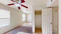 This single-story, 3-bedroom, 1-bathroom home offers a well-organized layout that makes efficient use of its space. The interior is designed with practicality in mind, featuring a consistent color palette of neutral tones throughout.

The kitchen is a standout feature, equipped with warm-toned wooden cabinetry extending to the ceiling for ample storage, light tile flooring, and a full suite of black appliances including a gas range with overhead microwave, dishwasher, and refrigerator. A pendant light illuminates a dining nook adjacent to the kitchen, which benefits from natural light through a window with blinds.

Each of the three bedrooms is carpeted and equipped with a ceiling fan and light fixture. The generously sized primary bedroom includes a built-in closet with a full-length hanging rod, offering practical storage. The additional bedrooms each feature natural light from windows and their own closet space.

The single bathroom is tiled and includes a full soaking tub and shower combination, a wooden vanity with a countertop sink, a toilet, and a built-in shelving unit for added storage.

A hallway connects the rooms, providing a logical flow throughout the home. Overall, the space presents a clean, functional, and well-lit environment suited for comfortable everyday living.