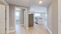 Located at 135 Stevens Ave in Little Falls, NJ, this thoughtfully updated single-floor residence offers a clean, contemporary aesthetic defined by light hardwood-style flooring, neutral gray tones, and abundant natural light throughout. The open-concept living and dining area flows seamlessly into the kitchen, creating an inviting, connected space ideal for both everyday living and entertaining. The kitchen is well-appointed with white shaker cabinetry, white quartz countertops, stainless steel appliances including a refrigerator and microwave, a tiled backsplash, and a peninsula with pendant lighting that doubles as a casual dining bar. A separate kitchen corridor provides additional counter space and storage, enhanced by a large window overlooking the neighborhood. The bedrooms are generously proportioned, each featuring light flooring, recessed lighting, and windows that bring in natural light; one bedroom includes a ceiling fan for added comfort. The two bathrooms are finished in a striking monochromatic palette, with white cabinetry, dark granite countertops, and matte black fixtures. One bathroom offers a soaking tub with chevron-tiled surround, while the other features a glass-enclosed walk-in shower. Dark floor tiles ground both spaces with a bold, modern contrast. Throughout, crisp white trim and recessed lighting contribute to a polished, move-in-ready atmosphere.