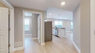Located at 135 Stevens Ave in Little Falls, NJ, this thoughtfully updated single-floor residence offers a clean, contemporary aesthetic defined by light hardwood-style flooring, neutral gray tones, and abundant natural light throughout. The open-concept living and dining area flows seamlessly into the kitchen, creating an inviting, connected space ideal for both everyday living and entertaining. The kitchen is well-appointed with white shaker cabinetry, white quartz countertops, stainless steel appliances including a refrigerator and microwave, a tiled backsplash, and a peninsula with pendant lighting that doubles as a casual dining bar. A separate kitchen corridor provides additional counter space and storage, enhanced by a large window overlooking the neighborhood. The bedrooms are generously proportioned, each featuring light flooring, recessed lighting, and windows that bring in natural light; one bedroom includes a ceiling fan for added comfort. The two bathrooms are finished in a striking monochromatic palette, with white cabinetry, dark granite countertops, and matte black fixtures. One bathroom offers a soaking tub with chevron-tiled surround, while the other features a glass-enclosed walk-in shower. Dark floor tiles ground both spaces with a bold, modern contrast. Throughout, crisp white trim and recessed lighting contribute to a polished, move-in-ready atmosphere.