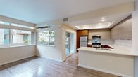 This single-story, 2-bedroom, 2-bathroom residence at 200 Greenbriar Cir in Petaluma, California offers a well-designed layout with a clean, modern aesthetic. The open-concept living and kitchen area is anchored by warm hardwood-style flooring and large windows that invite generous natural light, with a sliding glass door providing direct access to an outdoor patio and views of mature trees and landscaping.

The kitchen is a standout feature, showcasing two-tone cabinetry — rich walnut lower cabinets paired with light gray upper cabinets — complemented by white quartz countertops, a subway tile backsplash, and a full suite of stainless steel appliances including a gas range, microwave, and refrigerator. A peninsula island adds additional counter space and enhances the open flow between the kitchen and living area.

Both bedrooms feature plush carpeting and neutral wall tones, offering a calm and comfortable atmosphere. The primary bedroom is generously sized, while the second bedroom provides flexible space for various needs. Both bathrooms are finished with tub/shower combos with chrome fixtures and hardwood-style flooring. A hallway with a closet adds practical storage to this efficiently arranged home.