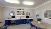 Located in Oak Grove, Houston, TX, this single-floor community space offers a well-designed environment tailored for both focused work and collaborative gatherings. The interior is defined by a cohesive blue and neutral color palette, with warm beige walls, crown molding, and plush patterned carpeting throughout.

The centerpiece of the space is a built-in dual workstation featuring bold navy cabinetry with gold hardware, a continuous white countertop, and dual monitors. Above the workstation, a series of white floating shelves display curated greenery, decorative vases, and accent pieces, adding a polished, welcoming feel. Two circular black-framed mirrors anchor the wall, lending a modern touch.

Multiple round wood tables paired with teal and navy upholstered chairs provide ample seating for small group meetings or informal collaboration. Large windows with white blinds along one wall allow natural light to fill the room while offering views of the surrounding greenery outside.

A pass-through window connects to an adjacent area, enhancing the open, communicative flow of the space. Recessed and flush-mount ceiling fixtures provide bright, even lighting throughout. A connecting hallway leads to additional rooms, extending the overall functionality of this thoughtfully appointed community facility.
