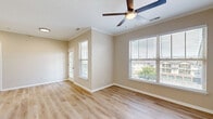 This thoughtfully designed one-bedroom, one-bathroom residence in Bolingbrook, Illinois offers a functional and comfortable single-floor layout. The open-concept living room and kitchen area is bright and welcoming, featuring light wood-tone luxury vinyl plank flooring, neutral beige walls, crown molding, and a ceiling fan with light fixture. Multiple windows dressed with horizontal blinds allow generous natural light and views of the surrounding community. The kitchen is well-equipped with white shaker-style cabinetry, light quartz countertops, a peninsula with an undermount sink, and a full suite of stainless steel appliances including a refrigerator, electric range, and microwave. A dedicated utility area and closet provide practical storage solutions. The bedroom is carpeted for comfort, featuring a ceiling fan and a window with outdoor views. The bathroom includes a white vanity with quartz countertop, overhead cabinetry, a full tub-shower combination with white tile surround, and light hardwood-style flooring. Clean white trim and consistent neutral tones throughout give the space a cohesive, move-in-ready aesthetic.