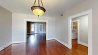 Located at 855 Mulberry St in Macon, Georgia, this single-story home offers a thoughtfully arranged layout with 2 bedrooms, 2 bathrooms, a living room, dining room, kitchen, laundry, utility room, and an impressive five closets throughout. Rich, dark hardwood floors run consistently throughout the home, lending warmth and character to every room. The dining room makes a strong first impression with a classic pendant light fixture and open views into the living room, which features French doors that invite natural light and provide outdoor access. A built-in cabinetry nook is also visible from the dining area, adding a charming, functional detail. The living room showcases textured walls and a large set of French doors, creating a bright and inviting atmosphere. The kitchen is well-proportioned, featuring deep cherry-toned cabinetry, a gas range, and dual windows that fill the space with natural light. The bedrooms are comfortably sized, each equipped with ceiling fans and multiple windows. The primary bedroom benefits from generous closet access. The bathrooms retain classic character, with one featuring white subway tile, a navy accent border, and a soaking tub beneath a natural light window. Two connecting hallways ensure smooth flow throughout the home.