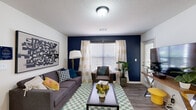 This efficient and thoughtfully designed 1-bedroom, 1-bathroom unit maximizes every square foot across a single floor. The living room makes a strong first impression with a bold navy accent wall, wood-style plank flooring, a textured ceiling, and windows that invite ample natural light. A sliding glass door provides direct outdoor access, enhancing the open feel of the space.

The kitchen is well-appointed with crisp white shaker-style cabinetry, granite-look countertops, and a full suite of stainless steel appliances, including a refrigerator, range, microwave, and dishwasher. The L-shaped layout offers generous counter and storage space, making it highly functional.

The bedroom is a comfortable retreat, featuring a ceiling fan, a large closet, and a window with outdoor views. The room provides enough space for a full sleeping area and a dedicated workspace or study area.

The bathroom includes a full tub-shower combination with clean white tile surround, maintaining a bright and functional design. A dedicated laundry area completes the unit, adding everyday convenience. Wood-style flooring runs throughout, tying all spaces together with a cohesive, modern aesthetic.