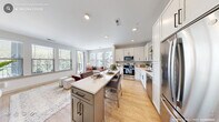 Located in Cary, NC, this well-appointed 3-bedroom, 2-bathroom single-floor home offers a thoughtfully designed open-concept layout filled with natural light and contemporary finishes. The kitchen is a standout feature, boasting white shaker cabinetry with matte black hardware, a subway tile backsplash, stainless steel appliances, quartz countertops, and a central island with seating — seamlessly flowing into the living area. The living room is bright and welcoming, with large windows dressed in clean white blinds and a glass door opening to a private balcony. The balcony, accented with bold blue columns and a warm wood-paneled ceiling, offers pleasant views of surrounding greenery. The generously sized primary bedroom features plush carpeting, a walk-in closet with built-in shelving, and direct access to a well-designed bathroom with a sleek vanity and quartz countertop. The additional bedrooms offer flexible use, with one shown as a versatile office or flex room. Both bathrooms echo the home's modern aesthetic with light wood-look flooring. A dedicated in-unit laundry room with full-size washer and dryer adds everyday convenience. Light-toned wood flooring, recessed lighting, and a neutral palette tie the entire home together in a clean, modern aesthetic.