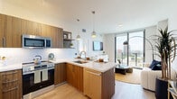 Located at 225 SW Tenth Street in Miami's vibrant Brickell neighborhood, this thoughtfully designed one-bedroom, one-bathroom residence offers a contemporary open-concept layout with clean lines and warm, modern finishes throughout. Light wood-toned flooring runs seamlessly across the entire unit, complemented by crisp white walls that enhance the sense of brightness and space.

The kitchen serves as a central hub, featuring rich wood cabinetry, white quartz countertops, a white subway tile backsplash, and a full suite of stainless steel appliances including a French door refrigerator, range, and microwave. A peninsula with bar seating and pendant lighting above creates a natural gathering space that flows into the living area. Open shelving adds both functionality and style.

Floor-to-ceiling sliding glass doors in the living area open to a private balcony, flooding the space with natural light and framing sweeping views of the Miami skyline. The bedroom features large windows with the same striking city views, light hardwood flooring, and a dedicated closet for ample storage.

The bathroom is sleek and spa-inspired, with a walk-in glass shower, white subway tile walls, a floating wood vanity with a white quartz countertop, and a large backlit mirror. Every detail reflects a refined, modern aesthetic suited to urban living in the heart of Miami.