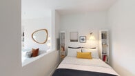 Located on Wilshire Boulevard in Los Angeles, this single-floor unit offers a well-designed contemporary living space with a clean, modern aesthetic throughout. The layout, as seen in the floor plan, efficiently connects the living area, bedroom, kitchen, and bathroom in a cohesive flow with light wood-style flooring running through the common areas.

The kitchen is a standout feature, showcasing textured gray laminate cabinetry extending to the ceiling, white quartz countertops, and a full suite of stainless steel appliances including a gas range, built-in microwave, and refrigerator. A central island with a stainless steel surface provides additional workspace, while a window with a roller shade allows natural light to filter in.

The bedroom is thoughtfully designed with flanking built-in shelving units that frame the sleeping area, providing ample storage. Crisp white walls and soft ambient lighting contribute to a calm, restful atmosphere.

The bathroom maintains the unit's modern character with floor-to-ceiling white subway tile surrounding the bathtub and shower combination, light tile flooring, and wood-toned vanity cabinetry. Clean lines and recessed lighting complete the space. Overall, the unit presents a cohesive, contemporary interior well-suited to urban living.