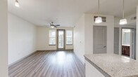 Located in Richmond, TX, this single-floor residence offers 2 bedrooms and 3 bathrooms with a well-considered layout across a comfortable footprint. The kitchen is a standout feature, showcasing rich dark-wood cabinetry, granite countertops, stainless steel appliances, and a central island with pendant lighting — all set on durable wood-look flooring that extends into the living room. The living area is bright and open, with a ceiling fan and a door with windows allowing natural light to flow in. Both bedrooms feature plush carpeting and ceiling fans. The generously sized primary bedroom includes direct access to a private en-suite bathroom and a dedicated closet, offering added convenience and privacy. The bathrooms are finished with dark-wood vanities and granite countertops, complementing the kitchen's aesthetic. One bathroom features a tiled tub-shower combination with wood-look flooring. Panel-style interior doors with brushed nickel hardware add a clean, modern touch throughout. Two closets provide practical storage solutions. The neutral color palette of cream walls and light flooring creates a bright, cohesive ambiance across the entire space.
