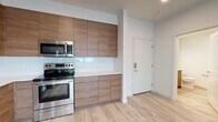 Located on the 7th floor at 3214 Broadway in Everett, WA, unit 701 is a thoughtfully designed modern residence that combines clean contemporary aesthetics with functional living. Light-toned luxury vinyl plank flooring extends throughout the entire unit, creating a bright and cohesive feel. The open-concept living area is bathed in natural light from large windows that frame elevated views of the Everett cityscape, and a ceiling fan adds practical comfort to the space.

The kitchen is a standout feature, outfitted with full-height wood-toned cabinetry, white quartz countertops, a glossy white tile backsplash, and a complete suite of stainless steel appliances including a refrigerator, electric range, built-in microwave, and dishwasher. The layout connects seamlessly to the main living area, making it ideal for everyday living and entertaining.

The bedroom offers a calm retreat with a ceiling fan, a generously sized window showcasing city views, and ample wall space. The unit includes two bathrooms, each finished with wood-grain vanities, white quartz countertops, large mirrors, and light flooring. One bathroom features a full tub/shower combination, while the other is appointed as a three-quarter bath, both maintaining the unit's clean, modern design language throughout.