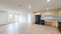 This well-designed 3-bedroom, 2-bathroom residence on 3rd St SW in Kasson, MN offers a thoughtfully laid-out single-floor plan with a clean, modern aesthetic throughout. Light wood-tone flooring flows seamlessly across the entire unit, creating a bright and cohesive feel in every room.

The open-concept kitchen and living area serves as the heart of the home. The kitchen is generously sized, featuring light maple cabinetry that extends to the ceiling for ample storage, granite countertops, and black appliances including a refrigerator, range, microwave, and dishwasher. Recessed lighting illuminates the space effectively.

The living area is open and airy, with natural light streaming in from a balcony-facing door that provides direct outdoor access. The balcony offers views of the surrounding area.

All three bedrooms are well-proportioned, with the primary bedroom offering its own dedicated closet space. A total of four closets are distributed throughout the unit, providing excellent storage. The bedrooms maintain the same light flooring and neutral wall tones found throughout.

Both bathrooms feature granite-topped vanities with light maple cabinetry, matching the kitchen's design language. The bathrooms are equipped with accessibility-friendly grab bars and walk-in showers. A dedicated laundry room with an in-unit washer adds everyday convenience, complemented by a separate utility room.