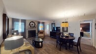 This single-floor residence offers a thoughtfully designed layout that balances comfort and functionality throughout. The open-concept living and dining area serves as the heart of the home, anchored by a classic fireplace with a decorative mantel and complemented by rich hardwood-style flooring. A statement pendant light illuminates the dining space, while large windows dressed with flowing drapes fill the area with natural light and provide a welcoming ambiance. The living room features vaulted accent walls and offers direct access to an exterior door, adding convenience and connectivity to the outdoors.

The galley-style kitchen is outfitted with rich, dark wood cabinetry, white countertops, and standard appliances including an electric range and dishwasher, with a pantry closet providing additional storage.

Two well-sized bedrooms are carpeted for warmth and comfort. The primary bedroom includes an accent wall and ample space for a full furniture arrangement, while a second bedroom benefits from a large window offering views of the surrounding greenery. Both bathrooms are functional and clean in design — one featuring a vanity with dark wood cabinetry and a tub-shower combination, and the other a tiled shower with a decorative curtain. Throughout, the space maintains a cohesive, contemporary aesthetic.