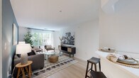 This single-floor residence at 11420 Esplanade Drive in Reston, Virginia, offers a well-designed layout with a clean, contemporary aesthetic throughout. Light wood flooring flows consistently across the living areas, dining room, kitchen, and bedrooms, creating a cohesive and airy feel.

The living room is a welcoming space highlighted by a large window that draws in abundant natural light and offers views of surrounding greenery. A distinctive blue-gray accent wall adds depth and contrast against the otherwise bright, white walls. The dining area sits adjacent to the main living space, providing a defined yet open setting for everyday meals.

The kitchen features light wood cabinetry paired with stainless steel appliances, including a refrigerator, gas range, and built-in microwave, along with a convenient pass-through counter connecting to the main living area.

The primary bedroom includes a sliding glass door leading to a private outdoor space, a bold accent wall, and ample room for a generous furniture arrangement. The second bedroom receives natural light through a large window with outdoor views. Both bathrooms are finished with warm wood vanities, wide mirrors, and tub-shower combinations, maintaining the residence's consistent, understated design throughout.