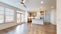 Located in San Antonio, TX, this well-designed single-story, 3-bedroom, 1-bathroom home offers a thoughtfully planned open-concept layout with contemporary finishes throughout. The living and dining areas flow seamlessly together beneath recessed lighting and a ceiling fan, with rich hardwood-style flooring underfoot and large French doors that invite natural light and provide access to a private balcony overlooking the surrounding community. The kitchen is a standout feature, showcasing light wood flat-front cabinetry, a marble-style tile backsplash, granite countertops, a center island with additional counter space, and a full suite of stainless steel appliances including a refrigerator with water dispenser, electric range, built-in microwave, and dishwasher. Two pantries provide ample storage. The primary bedroom is a comfortable retreat, complete with a ceiling fan, walk-in closet with built-in shelving and hanging rods, and an en-suite bathroom featuring a granite-topped vanity, wood-tone cabinetry, a walk-in shower with marble-style tile, and direct closet access. Secondary bedrooms offer plush carpeting and generous closet space. A dedicated laundry area and utility room add everyday practicality to this move-in-ready home.