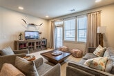 This single-floor residence offers a thoughtfully designed open-concept layout that seamlessly connects the kitchen, dining, and living areas. The kitchen is a standout feature, showcasing rich dark gray cabinetry with sleek bar-pull hardware, light granite countertops, a classic white subway tile backsplash, and a full suite of stainless steel appliances including a French door refrigerator, electric range, and built-in microwave. A large central island with granite countertop provides bar seating for multiple guests and serves as the heart of the space. Wood-look flooring extends throughout the main living areas, adding warmth and continuity. The living room benefits from natural light through large windows dressed with draping curtains, recessed lighting, and ample room for comfortable seating arrangements. The bedrooms are carpeted and generously sized, each featuring ceiling fans and windows that invite natural light. The bathrooms are elegantly finished with dark vanity cabinetry, granite countertops, subway tile tub-shower surrounds, and industrial-style lighting fixtures. Dual vanity sinks are featured in at least one bathroom, adding a practical luxury. The overall ambiance of the space is modern, cohesive, and inviting, with consistent high-quality finishes carried throughout every room.