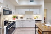 Located at 1401 Creston Rd in Paso Robles, CA, this single-story, three-bedroom, two-bathroom home offers a thoughtfully designed layout across a compact yet efficiently utilized floor plan. The kitchen is a standout feature, showcasing white shaker cabinetry extending to the ceiling, white quartz countertops, stainless steel appliances including a gas range, built-in microwave, and dishwasher, complemented by light wood-style flooring and recessed lighting. The living room offers a warm, inviting atmosphere with light-toned walls, wood-style flooring, and windows that allow natural light to filter through sheer curtains, with access to an outdoor area. The generously sized primary bedroom features carpet flooring, a bold accent wall, a mirrored sliding closet, and a window admitting ample natural light. Additional bedrooms share similar carpeted flooring and neutral tones. The primary bathroom includes a dual-sink white vanity with a large mirror, while the second bathroom features a white vanity and a shower-tub combination. Throughout, the home maintains a clean, contemporary aesthetic with a cohesive, neutral color palette.