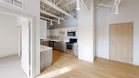 This contemporary apartment in Saint Paul, MN, offers 710 square feet of thoughtfully designed living space. The industrial-inspired architecture is evident in the exposed ductwork and beam ceilings, adding character and height to the rooms. Large windows flood the space with natural light, providing picturesque views of the surroundings.

The open-concept layout features a modern kitchen with a mix of white and wood-grain cabinetry, stainless steel appliances, and ample counter space. The living area seamlessly connects to the kitchen, creating an ideal space for entertaining or relaxing.

Two bedrooms, including a spacious 140 square foot primary bedroom, offer comfortable retreats. The bathrooms are sleek and functional, with one featuring a wood-grain vanity and large mirror. Plush carpeting in the bedrooms contrasts with the warm wood flooring in the main living areas and kitchen.

Additional amenities include in-unit laundry facilities and closet space. The apartment's design maximizes the use of space, creating a cozy yet open feel throughout. Its location at 1554 Midway Pkwy in Saint Paul puts residents close to urban conveniences while providing a comfortable home environment.