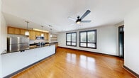 Located at 2005 East Franklin Street in Richmond, Virginia, Unit 318 at Old Stone is a thoughtfully laid-out one-bedroom, one-bathroom residence that makes efficient use of its single-floor plan. The open-concept living and kitchen area serves as the heart of the unit, featuring warm bamboo-style hardwood flooring that extends throughout the main living space. The kitchen is a standout feature, appointed with light wood cabinetry, dark granite countertops, a peninsula with a double-basin sink, and a full suite of stainless steel appliances including a refrigerator, electric range, and over-the-range microwave. Pendant lighting above the peninsula adds a modern, polished touch. The bedroom offers a cozy, private retreat with rich dark hardwood flooring, a window with blinds that allows for natural light and outdoor views, and a ceiling fan for added comfort. A dedicated closet provides practical storage. The bathroom is cleanly finished with large-format gray tile flooring, a tub-shower combination featuring vertically tiled walls with a decorative mosaic accent strip, a wooden vanity with a dark countertop, and recessed lighting. The overall aesthetic is modern and cohesive throughout the unit.