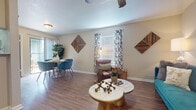 Located at 11910 Thoroughbred Dr in Houston, Texas, this single-floor residence offers a well-designed layout with a cohesive contemporary aesthetic. The open living and dining area serves as the heart of the home, featuring warm wood-look flooring, ceiling fans, and natural light streaming through windows dressed with patterned curtains. The living space is thoughtfully arranged, with room for both a seating area and a dedicated dining space, accented by decorative wood-panel wall art that adds a rustic-modern touch.

The kitchen is a galley-style layout lined with white cabinetry, light countertops, a subway tile backsplash, and black appliances including a gas range, microwave, refrigerator, and dishwasher — providing ample functionality and storage.

The home includes two bedrooms, each with plush carpeting, ceiling fans, and natural light from well-placed windows. The primary bedroom is generously proportioned and features walk-in closet access. The secondary bedroom also provides closet space and a comfortable, calm atmosphere.

Two full bathrooms serve the residence, each equipped with a shower-tub combination and updated white vanity cabinetry. Wood-look flooring extends into the bathrooms, maintaining a consistent design language throughout this well-appointed Houston home.