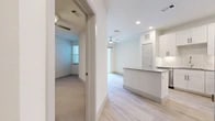 This thoughtfully designed single-floor residence offers a bright, modern living experience with a clean, open layout and contemporary finishes throughout. Light wood-style flooring flows through the main living areas, complemented by crisp white walls and recessed lighting that create a fresh, airy ambiance.

The kitchen is a standout feature, boasting white shaker-style cabinetry extending to the ceiling for ample storage, a subway tile backsplash, granite countertops, and a central island that doubles as a breakfast bar. Stainless steel appliances — including a range, built-in microwave, dishwasher, and refrigerator — complete the space with a polished, functional finish.

The open living area connects seamlessly to the kitchen, featuring a ceiling fan and windows that allow natural light to brighten the space. The bedroom is a comfortable retreat with plush carpeting, a ceiling fan, and a window that brings in natural light. It provides direct access to the full bathroom.

The bathroom is well-appointed with a granite-topped vanity, white cabinetry with matte black hardware, a soaking tub with tile surround, and light wood-style flooring. Adjacent to the bathroom is a dedicated closet with built-in shelving and rod storage, adding practical organization to this efficiently planned home.