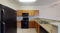 This single-story space is designed with a practical, comfortable layout that flows naturally between its key areas. The kitchen serves as a functional hub, equipped with warm honey-toned cabinetry, granite-look countertops, and a full suite of black appliances including a refrigerator, electric range, over-the-range microwave, and a double-basin stainless steel sink. Light wood-style flooring and a skylight fixture keep the space bright and easy to maintain.

Adjacent to the kitchen, the dining and living areas feature the same light wood-style flooring, crown molding, and ceiling fans with light fixtures, creating a cohesive and airy atmosphere. Natural light enters through blinded windows, enhancing the warm, neutral color palette used consistently throughout the unit.

The bedrooms are carpeted in a neutral tone and offer a quiet, comfortable retreat. Each room includes windows with blinds, providing natural light while maintaining privacy. Ceiling fans are present in select rooms for added comfort.

The bathrooms are finished with light wood-style flooring, granite-look countertops atop wood-toned vanities, and full tub-shower combinations with curved curtain rods—balancing both style and utility throughout the space.