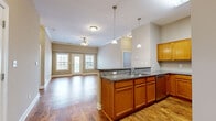 Located at 275 New Towne Dr in Bowling Green, KY, this 2-bedroom, 2-bathroom single-floor residence offers a well-designed layout with a comfortable, functional feel throughout. The open-concept kitchen and living area serves as the heart of the home, featuring warm honey-toned cabinetry, granite countertops, a breakfast bar with seating, stainless steel appliances, and pendant lighting overhead. Hardwood-style flooring flows through the main living areas, complemented by neutral taupe walls and crown molding in the living room. A ceiling fan and French doors with flanking windows flood the living room with natural light and provide access to the outdoors. The primary bedroom is generously sized and includes a walk-in closet equipped with wire shelving and a full en-suite bathroom with a combined tub and shower and a wood-toned vanity. The second bedroom is carpeted and features its own closet with built-in wire shelving. Both bathrooms echo the warm cabinetry tones found throughout the home. A utility room adds practical storage. The consistent use of warm, neutral tones and quality finishes creates a cohesive and inviting atmosphere across every room.