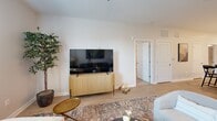 Located at 100 Fair Oaks Dr in Savannah, GA, this well-appointed one-bedroom, one-bathroom residence offers a thoughtfully designed open-concept layout. The combined kitchen and living area forms the heart of the home, where crisp white shaker cabinetry, quartz countertops, and a full suite of stainless steel appliances — including a refrigerator, range, and microwave — create a clean, modern aesthetic. A central kitchen island with an undermount sink and bar seating provides a natural gathering point that flows seamlessly into the living area, which features light wood-style flooring, recessed lighting, and a ceiling fan. The living room offers generous wall space and natural light from a large window dressed with draping curtains. The bedroom is a calm retreat, carpeted for comfort, with a ceiling fan, window with natural light, and direct access to both a spacious walk-in closet outfitted with multi-tier wire shelving and the full bathroom. The bathroom features a white vanity with a quartz countertop, a tub-shower combination with tile surround, and wood-style flooring. Throughout the residence, a neutral color palette and clean finishes contribute to a cohesive, contemporary ambiance.