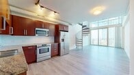 This two-story property offers 1080 square feet of living space, efficiently distributed across two floors. The ground floor spans 500 square feet, while the upper level provides 570 square feet of additional space. The layout includes two bathrooms, a hallway, an entrance, and a combined kitchen and living room area.

The interior showcases a bright and airy ambiance, emphasized by pristine white walls and ample natural light. A standout feature is the modern ceiling fan with sleek blue blades, providing both style and functionality. The space boasts an open concept design, with a notable balcony or terrace access visible through glass doors, offering an extension of the living area and potential outdoor views.

Flooring appears to be a neutral-toned carpet, adding warmth to the space while maintaining a contemporary feel. The room's clean lines and minimal design suggest a modern architectural approach, with attention to detail evident in features like the crown molding and recessed lighting. Overall, the property presents a blank canvas, ready for personalization while offering contemporary comforts and a spacious feel.