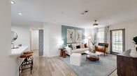 This thoughtfully designed 2-bedroom, 1-bathroom residence offers a cohesive and modern aesthetic across its single floor. Light wood-style flooring runs throughout, complemented by crisp white walls and distinctive teal accent walls that lend a consistent, calming palette to the space.

The living room serves as the heart of the home, featuring crown molding, a ceiling fan, and large windows that invite abundant natural light and outdoor views. The adjoining dining area continues the teal accent theme and benefits from the same bright, open atmosphere.

The galley-style kitchen is efficiently laid out with grey cabinetry, white countertops, a stainless steel sink, and a full suite of stainless steel appliances, including a refrigerator, oven, and microwave.

The primary bedroom is generously proportioned, highlighted by a teal accent wall, a ceiling fan, and wide windows framing outdoor greenery. It also features a closet with mirrored sliding doors. The second bedroom maintains the same airy feel with neutral tones and natural light.

The bathroom is well-appointed with grey cabinetry, a large framed mirror, white countertops, and a tub-shower combination. A hallway and dedicated closet complete the practical layout of this well-balanced residence.
