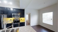 Located at 4405 Waterford Valley Dr in Durham, North Carolina, this single-floor residence offers a thoughtfully designed interior with contemporary finishes throughout. The kitchen is a standout feature, showcasing dark cabinetry that creates a striking contrast against light granite countertops. A vibrant yellow tile backsplash adds a bold pop of color, while stainless steel appliances — including a range with double ovens and an over-the-range microwave — provide both style and functionality. The kitchen flows seamlessly into an adjacent dining or living area, where rich, dark hardwood flooring anchors the space. Natural light pours in through multiple windows fitted with white blinds, contributing to a bright and welcoming atmosphere. The textured ceiling adds subtle architectural interest, while clean white walls keep the overall aesthetic fresh and modern. A hallway visible from the kitchen leads to additional rooms, hinting at a well-connected and practical floor plan. The combination of bold design choices and quality materials gives this residence a polished, move-in-ready feel that balances everyday comfort with contemporary style.