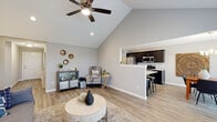 Located at 3115 Carroll Rd in Fort Wayne, Indiana, this single-story home offers a thoughtfully designed floor plan with three bedrooms, two bathrooms, a dedicated laundry room, and ample hallway and closet storage. The living room immediately impresses with soaring vaulted ceilings and a ceiling fan, creating an airy, open feel. Light-toned hardwood-style flooring runs throughout, tying the spaces together with a clean, contemporary aesthetic. The kitchen features dark espresso cabinetry, granite countertops, stainless steel appliances including a gas range, microwave, dishwasher, and refrigerator, and a raised breakfast bar with seating. It opens seamlessly into the dining area, which is bathed in natural light from large windows and a sliding glass door offering pleasant outdoor views, all accented by a chandelier overhead. The bedrooms are comfortably sized, with the primary bedroom featuring access to a walk-in closet. The bathrooms are finished with dark cabinetry and granite-topped vanities, consistent with the home's modern design language. The dedicated laundry room includes side-by-side washer and dryer units with built-in shelving above. Throughout the home, neutral gray walls and white trim create a bright, cohesive, and move-in-ready environment.