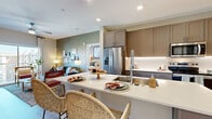 Located in Avondale, Arizona, this well-designed two-bedroom, two-bathroom residence offers a thoughtful single-level layout with modern finishes throughout. The open-concept kitchen is a standout feature, showcasing two-tone cabinetry in warm taupe and grey, stainless steel appliances, under-cabinet lighting, white quartz countertops, and a peninsula island with seating — ideal for both cooking and casual dining. The kitchen flows seamlessly into the living area, which features light wood-look flooring and a clean, neutral palette.

Both bedrooms are generously proportioned, carpeted for comfort, and equipped with ceiling fans and large windows that allow ample natural light. The primary bedroom connects to a well-appointed en-suite bathroom featuring a dual-sink vanity with backlit mirrors, a glass-enclosed walk-in shower with floor-to-ceiling tile, and wood-look flooring. Each bedroom is served by its own closet — one a walk-in with built-in shelving and dual hanging rods, the other a reach-in with shelving and hanging storage. The living room features light wood-look flooring and a smart thermostat panel. Throughout the home, recessed lighting, clean white ceilings, and consistent finishes create a cohesive, contemporary ambiance.
