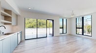 This contemporary single-story unit offers four bedrooms and five bathrooms, thoughtfully designed with a clean, modern aesthetic throughout. Light-toned hardwood flooring flows seamlessly across living areas, bedrooms, and hallways, complemented by crisp white walls and matte black hardware accents on doors and fixtures.

The kitchen is a standout feature, equipped with stainless steel appliances including a gas range, microwave, and dishwasher. Two-toned cabinetry pairs light wood uppers with slate blue lowers beneath white countertops, creating a contemporary and functional workspace.

A spacious main living area is bathed in natural light, courtesy of expansive floor-to-ceiling black-framed sliding glass doors that open directly onto a generous outdoor terrace. Additional bedrooms feature large picture windows that bring in abundant daylight and offer views of the surrounding neighborhood.

The five bathrooms are finished with neutral large-format tile flooring, warm wood-toned vanities, and matte black fixtures. Bathrooms include walk-in tiled showers and well-appointed vanities with illuminated mirrors. Two dedicated closets, including a walk-in with built-in shelving, provide excellent storage. Three connecting hallways efficiently link the layout, ensuring smooth circulation throughout this well-appointed, light-filled space.