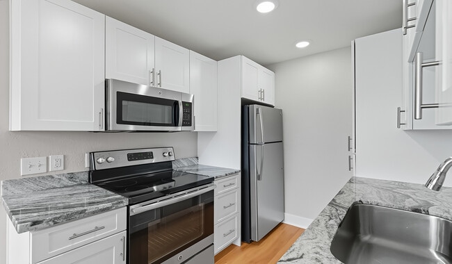 Modern kitchen with stainless steel appliances and granite countertops - Pacifica Park Apartments