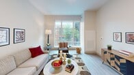 This 650-square-foot, two-bedroom, one-bathroom apartment at 2939 Smallman Street in Pittsburgh's Strip District offers a thoughtfully designed open-concept layout across a single floor. The combined kitchen and living area serves as the heart of the unit, featuring light wood-style flooring, exposed ductwork accents, and large windows that flood the space with natural light and urban views. The modern kitchen is equipped with stainless steel appliances, dark cabinetry, white quartz countertops, and a navy-blue island with seating for two, illuminated by pendant lighting. The living area provides a comfortable, airy atmosphere with ample wall space. The primary bedroom spans 140 square feet and includes large floor-to-ceiling windows, plush carpeting, and generous storage. The second bedroom mirrors this design with similar windows and elevated ceilings with exposed ductwork. The full bathroom features a clean, modern aesthetic with a wide vanity, white countertop, dark cabinetry, and a full soaking tub. A stacked in-unit washer and dryer adds everyday convenience. Throughout, neutral tones and contemporary finishes create a cohesive, move-in-ready living environment.