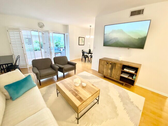 Sala de estar amueblada con pantalla plana, escritorio y puertas de patio. - 1131 Alta Loma Rd