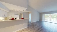 Located at 500 North Congress Avenue in Delray Beach, Florida, this 2-bedroom, 2-bathroom residence offers a thoughtfully designed single-floor layout. The open-concept living and dining area is immediately impressive, featuring soaring vaulted ceilings that enhance the sense of space and light-toned wood-look flooring that runs throughout. Sliding glass doors lead to a private balcony, bringing in natural light and outdoor views of the surrounding greenery.

The kitchen is positioned adjacent to the living area and features a raised breakfast bar, white cabinetry, a built-in cooktop, and a full-size refrigerator, all illuminated by track lighting overhead. A dedicated open shelving unit adds functional storage.

The primary bedroom is generously sized, benefiting from a large multi-pane window that fills the room with natural light. Both bedrooms offer wood-look flooring and ample closet space, including a walk-in closet with shelving in the second bedroom. The two bathrooms each include a full tub-shower combination with tiled surrounds and wood-look flooring. Neutral, soft-gray walls throughout the residence create a clean, cohesive aesthetic suitable for a variety of décor styles.