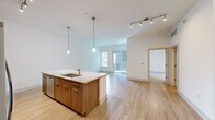 Located at 4150 Ashford Dunwoody Rd NE in Brookhaven, GA, this well-appointed one-bedroom, one-bathroom residence offers a thoughtfully designed single-floor layout. The open-concept kitchen and living area serves as the heart of the home, anchored by a large center island with granite countertops, an undermount sink, and elegant pendant lighting. Warm wood-tone cabinetry lines the kitchen walls, complemented by a full suite of stainless steel appliances including a refrigerator, range, and microwave. Light hardwood-style flooring extends throughout the main living areas, enhancing the bright, airy feel. The living room opens to a private balcony through sliding glass doors, allowing ample natural light to fill the space. The bedroom features plush carpeting, a ceiling fan, and a window with outdoor views. The bathroom is finished with tile flooring, a granite-topped vanity with wood cabinetry, a soaking tub with tile surround, and a separate glass-enclosed shower. A dedicated in-unit laundry room houses a full-size washer and dryer with built-in shelving for additional storage. A closet rounds out the functional layout of this modern Brookhaven residence.