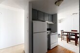 Located at 711 Arch St in Ann Arbor, Michigan, this three-bedroom, one-bathroom unit is arranged on a single floor with a functional and efficient layout. The space includes a living room, a dedicated dining area, a hallway, and two closets distributed throughout.

The kitchen features dark gray upper cabinetry, a full-size refrigerator, and an electric range with overhead ventilation. Hard surface flooring in this area transitions into carpet in the adjacent dining and living spaces, which are visible from the kitchen and benefit from natural light through nearby windows.

Each of the three bedrooms is carpeted and includes built-in closet shelving for storage. The primary bedroom is brightened by a large sliding window offering views of the surrounding neighborhood and greenery. The two additional bedrooms also feature windows that bring in natural light, with one offering a quieter, more enclosed feel and built-in double closet rods.

The bathroom includes a vanity with granite-style countertop, warm wood cabinetry, a wall-mounted mirror, and a combined tub-shower unit with a curtain rod. Dark hardwood flooring adds contrast to the light-toned walls throughout the bathroom. The unit provides a practical and straightforward layout well-suited for shared or multi-occupant living.