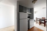 Located at 711 Arch St in Ann Arbor, Michigan, this three-bedroom, one-bathroom unit is arranged on a single floor with a functional and efficient layout. The space includes a living room, a dedicated dining area, a hallway, and two closets distributed throughout.

The kitchen features dark gray upper cabinetry, a full-size refrigerator, and an electric range with overhead ventilation. Hard surface flooring in this area transitions into carpet in the adjacent dining and living spaces, which are visible from the kitchen and benefit from natural light through nearby windows.

Each of the three bedrooms is carpeted and includes built-in closet shelving for storage. The primary bedroom is brightened by a large sliding window offering views of the surrounding neighborhood and greenery. The two additional bedrooms also feature windows that bring in natural light, with one offering a quieter, more enclosed feel and built-in double closet rods.

The bathroom includes a vanity with granite-style countertop, warm wood cabinetry, a wall-mounted mirror, and a combined tub-shower unit with a curtain rod. Dark hardwood flooring adds contrast to the light-toned walls throughout the bathroom. The unit provides a practical and straightforward layout well-suited for shared or multi-occupant living.