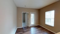 This single-floor unit in St. Andrews is designed with a functional, straightforward layout. Throughout the main living areas, rich dark hardwood-style flooring provides a clean, durable foundation, while warm neutral-toned walls create a consistent and cohesive atmosphere across all rooms.

The living area is bright and open, benefiting from multiple windows dressed with blinds that invite natural light. A glass-paneled exterior door provides additional light and outdoor access. The space connects seamlessly to the kitchen via a raised pass-through counter, which acts as a natural divider between the two areas. The kitchen is well-equipped with white appliances, including a refrigerator, electric range, built-in microwave, and dishwasher. Light wood cabinetry lines the upper and lower walls, offering ample storage, while recessed lighting overhead keeps the space well-lit. A double sink completes the practical setup.

The bedroom features wall-to-wall carpet for added comfort and includes a window overlooking greenery, providing a calm, private atmosphere. The bathroom is clean and utilitarian, equipped with a full-sized tub and shower combination, toilet, and textured walls finished in the same warm neutral palette found throughout the unit.