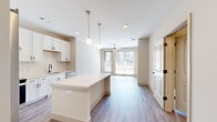 Located at 257 Indian Lake Blvd in Hendersonville, Tennessee, this thoughtfully designed one-bedroom, one-bathroom unit offers a clean, contemporary aesthetic throughout. The open-concept layout seamlessly connects the kitchen and living room, creating an airy, functional living space bathed in natural light from large windows and a glass sliding door that overlooks the surrounding community.

The kitchen is a standout feature, showcasing white shaker cabinetry with matte black hardware, a classic subway tile backsplash, quartz countertops, and a center island ideal for meal prep or casual dining. Stainless steel appliances, including a French door refrigerator, electric range, and dishwasher, complete the well-appointed space. Elegant pendant lighting illuminates the island, while recessed lighting and a ceiling fan keep the living area bright and comfortable.

The bedroom is carpeted for warmth and comfort, fitted with a ceiling fan, and features large windows that invite generous natural light. The bathroom offers a white vanity with quartz countertops, matte black fixtures, a large mirror, and a tiled walk-in shower. A dedicated laundry room with a front-load washer/dryer adds everyday convenience. Durable wood-look flooring flows throughout the main living areas, tying the modern design together cohesively.