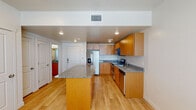 This single-floor residence offers a thoughtfully designed layout centered around a contemporary kitchen that serves as the heart of the space. The kitchen is outfitted with warm-toned wood cabinetry extending to the ceiling, providing generous storage. Granite countertops in a speckled gray tone run along the perimeter and top the substantial center island, which offers additional prep space and casual seating potential. Stainless steel appliances — including a French door refrigerator with ice and water dispenser, electric range, built-in microwave, and dishwasher — complete the kitchen's functional appeal. Light hardwood flooring flows seamlessly throughout the unit, lending a clean, cohesive aesthetic.

The bedroom is bright and open, featuring multiple windows that invite natural light, neutral white walls, and a ceiling fan for added comfort. The bathroom maintains the design consistency of the unit with matching wood cabinetry, a granite-topped vanity, a large mirror, and polished brushed-nickel fixtures. Recessed lighting throughout the main areas adds to the modern, well-lit ambiance, making the space feel inviting and move-in ready.