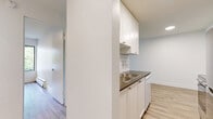 Located at 720 Queens Ave in New Westminster, BC, this one-bedroom, one-bathroom unit offers a thoughtfully designed layout across a single floor. Light-toned luxury vinyl plank flooring flows throughout the space, complementing the clean white walls and creating a bright, cohesive aesthetic.

The combined living and kitchen area forms the heart of the unit. The living room is generously proportioned, featuring large sliding glass doors that open to a private balcony overlooking lush greenery — filling the space with abundant natural light. A baseboard heating unit runs along the exterior wall for efficient climate control.

The galley-style kitchen is well-equipped with white shaker cabinetry, white subway tile backsplash, dark countertops, stainless steel appliances including an electric range and refrigerator, a built-in dishwasher, and a stainless steel double sink — maximizing both function and storage.

The bedroom is a comfortable, well-lit room featuring a sliding-door closet and a window with outdoor views, continuing the warm vinyl plank flooring found throughout the unit.

The bathroom is finished to a high standard, with classic white subway tile surrounding a full soaker tub and shower, a stone-topped vanity with an undermount sink, and neutral tile flooring — creating a clean, timeless look.