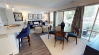 Located at 655 Americana Drive, this single-floor residence offers a seamlessly connected open-concept layout designed for comfortable everyday living. The modern kitchen is a standout feature, showcasing crisp white shaker cabinetry, a classic subway tile backsplash, granite countertops, stainless steel appliances, and a center island with bar seating — all illuminated by recessed lighting and elegant pendant fixtures. Rich hardwood-style flooring flows throughout, lending warmth and cohesion to the space. The dining area is positioned adjacent to the kitchen and anchored by a sliding glass door that opens to a private balcony, filling the space with generous natural light and outdoor views. The living room is generously proportioned, offering a welcoming atmosphere complemented by large sliding doors that extend the sense of space further toward the balcony. The bedroom is a serene retreat, featuring ample natural light from a wide window, access to a walk-in closet, and views into a secondary room. The bathroom is finished with granite countertops, an undermount sink, and a large framed mirror, maintaining the clean, refined aesthetic carried throughout the residence. Overall, the space presents a coastal-inspired palette with a polished, modern sensibility.