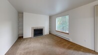 Located in Bothell, WA, this single-floor, 2-bedroom, 3-bathroom home offers a practical and comfortable layout across a well-utilized footprint. The living room serves as the heart of the space, featuring a tile-surround fireplace, built-in shelving on either side, plush carpeting, and a large window that frames views of lush greenery, filling the room with natural light. The adjoining dining area flows naturally from the living space, supporting an open, connected feel.

The kitchen is efficiently designed with light wood cabinetry, ample counter space, a double sink, and white appliances including a range, dishwasher, and refrigerator. The tile flooring adds a clean, durable finish to the cooking area.

Both bedrooms are carpeted and comfortably sized, with the primary bedroom offering generous proportions. A hallway with tile flooring leads through the home, flanked by closets with wood-paneled sliding doors. The three bathrooms include tub/shower combinations with clean white surrounds and tile flooring.

Additional highlights include an in-unit laundry room, a private balcony, and a textured-ceiling hallway that transitions smoothly between living and sleeping areas. Baseboard heating is present throughout. This home offers a cohesive, functional layout well-suited for everyday living.